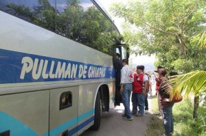 Voluntarios de la Cruz Roja abordan un autobús donde llegan niños y niñas migrantes en el puesto fronterizo hondureño de Corinto, para supervisar su estado y entregarles una bolsa de ayuda solidaria. Crédito: Thelma Mejía/IPS