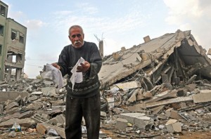 Abu Mohammed, cuya familia perdió su casa tras un bombardeo de Israel, desentierra papeles entre los escombros de un edificio de oficinas del gobierno en Gaza. Crédito: Eva Bartlett/IPS