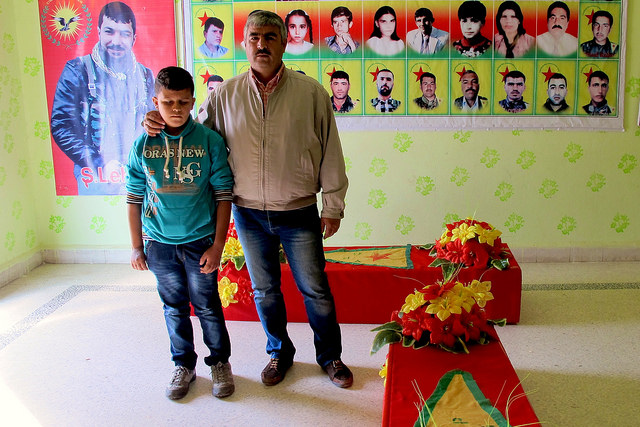Ali Jalil y su hijo Diar posan en la Asociación para los Mártires de Serekaniye, en la zona kurda de Siria, junto a dos ataúdes que acaban de preparar para muertos en combates con los extremistas yihadistas del Estado Islámico. Crédito: Karlos Zurutuza/IPS