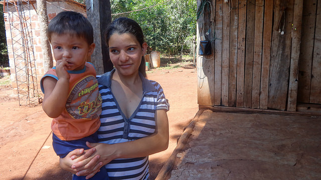 Soledad Olivera con su hijo en brazos, delante de su nuevo cuarto de baño, con inodoro y agua corriente, que reemplazó a una precaria letrina en su vivienda en un caserío de Bonpland, en la norteña provincia argentina de Misiones. Crédito: Fabiana Frayssinet/IPS