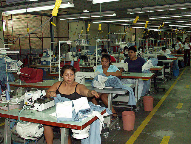 Trabajadoras confeccionan ropa deportiva de una marca estadounidense en una maquila de la Zona Franca de San Bartolo, en el municipio de Ilopango, en el este de El Salvador. En la planta trabajan 350 personas por cada turno de ocho horas, 80 por ciento mujeres, que ganan el salario mínimo. Crédito: Edgar Romero/IPS