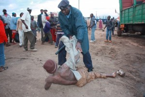 Un policía intenta levantar del suelo a un joven alcoholizado en la ciudad de Nyeri, en Kenia. Crédito: Miriam Gathigah/IPS