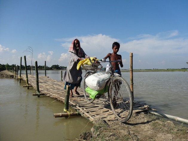 Las devastadoras inundaciones que en 2014 causaron estragos en el nororiental estado de Assam, en India, llevaron al gobierno a construir puentes de bambú. Este hombre y este niño van de una aldea a otra en barco y cruzan los puentes a pie. Crédito: Priyanka Borpujari/IPS