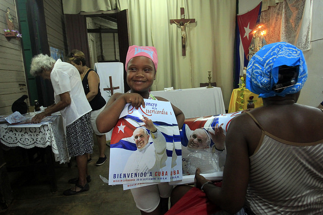 Una niña sostiene una pancarta de bienvenida al papa Francisco en la iglesia católica San Pablo Apóstol, ubicada en la localidad rural de Consejo Popular Pablo Noriega, en la provincia de Mayabeque, en Cuba. Crédito: Jorge Luis Baños/IPS