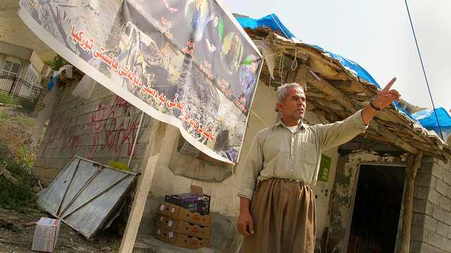 Rinaz Rojelat, el único comerciante que queda en la aldea de Zergely, en las montañas de Qandil, en el Kurdistán iraquí. Su negocio está justo frente a las ruinas de las casas destruidas de sus vecinos por el bombardeo de la aviación turca en agosto de este año. Crédito: Karlos Zurutuza/IPS