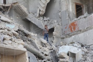 Residente de la ciudad siria de Aleppo en medio de un edificio bombardeado por las fuerzas del presidente Bashar al-Assad. Credit: Zak Brophy/IPS.