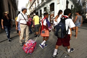 Dos estudiantes de la enseñanza primaria caminan próximo a un grupo de turistas extranjeros en una céntrica Plaza del centro histórico de La Habana Vieja, La Habana, Cuba. Crédito:Jorge Luis Baños/IPS.