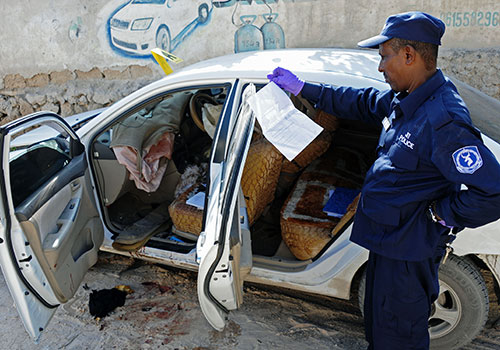Un policía investiga el asesinato de la periodista somalí Hindia Haji Mohamed, que murió cuando una bomba explotó en su automóvil en diciembre. Crédito: AFP / Mohamed Abdiwahab