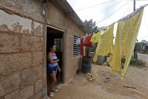 Yelenis Irán, de 32 años, quien trabaja en un hotel del balneario de Varadero, posa a la entrada de su vivienda, construida en el asentamiento informal de La Cartonera, en el extrarradio de la ciudad de Cárdenas, en Cuba, a donde migró con su familia desde el oriente del país. Crédito: Jorge Luis Baños/IPS