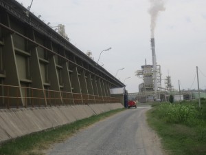 Un costado de los almacenes de del Complejo Agroindustrial Angostura SA (Caiasa), con la planta central al fondo, donde la caldera emite el único humo visible, de vapor, en esta procesadora de soja sin uso de combustibles fósiles y casi sin desechos de materia prima, a orillas del río Paraguay, en el municipio de Villeta, en Paraguay. Crédito: Mario Osava/IPS