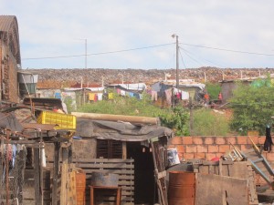 Abajo, casas destruidas por las inundaciones en Bañado Sur, uno de los barrios de población mayoritariamente pobre de las riberas del río Paraguay en Asunción. En el centro, las casuchas fabricadas algo más arriba por quienes se negaron a dejar el área, y al fondo el vertedero el basural que atrajo a muchos pobladores hacia este humedal con recurrentes inundaciones. Crédito: Mario Osava/IPS