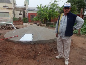 El campesino José Ramón Espinoza, al lado de una recién construida cisterna comunitaria para recoger el agua de lluvia, que permitirá a un grupo de familias mitigar las recurrentes sequías en Corzuela, un paraje rural de la norteña provincia de Chaco, en el norte de Argentina. El tanque subterráneo fue aportado por el Programa de Pequeñas Donaciones. Crédito: Fabiana Frayssinet/IPS