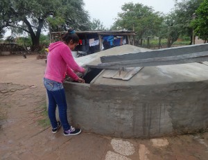 La joven Jésica Garay, estudiante de magisterio y madre de un bebe, saca agua de lluvia de la cisterna familiar instalada al lado de su humilde vivienda, en el municipio rural de Corzuela, en la provincia de Chaco, en el norte de Argentina. Crédito: Fabiana Frayssinet/IPS