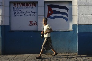 Una mujer camina por una calle céntrica de La Habana, delante de un grafiti en el que se observa la bandera de Cuba junto a la frase del líder histórico Fidel Castro: “Revolución es sentido del momento histórico. Es cambiar todo lo que debe ser cambiado”, que funciona como reclamo para el VII Congreso del Partido Comunista de Cuba. Crédito: Jorge Luis Baños/IPS