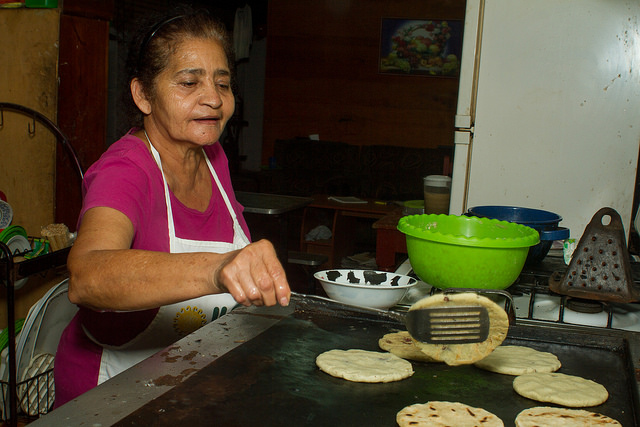 Juana Morales prepara popusas en su cocina. Una especie de tortillas, que los salvadoreños comen rellenas con variados productos, no son hechas con harina de maíz, sino con ojushte, una semilla muy nutritiva, cuyo consumo se promueve en el pueblo de San Isidro, en el occidente de El Salvador. Crédito: Edgardo Ayala/IPS