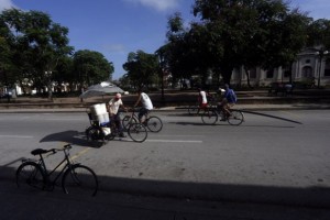 Un transeúnte carga con recipientes de agua en una especie de sidecar acoplado a su bicicleta en la ciudad de Holguín, en el oriente de Cuba. Los habitantes de la urbe tratan de acceder a la escasa agua por las vías disponibles a su alcance. Crédito: Jorge Luis Baños/IPS