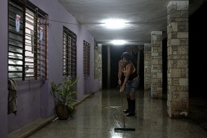 Una trabajadora limpia el suelo del corredor de una vivienda en Wajay, en el oeste de La Habana, en Cuba. El empleo en el servicio doméstico crece en el país, realizado casi siempre por mujeres, solo durante el día y muchas veces de manera informal. Crédito: Jorge Luis Baños/IPS