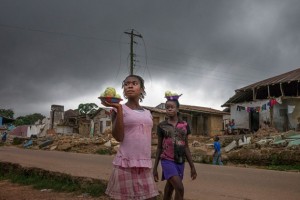 La infraestructura de Liberia fue destruida durante la guerra civil (1989-2003). Unas niñas caminan en el pueblo de Totota, en el condado de Bong, mirando las vivendas demolidas por las autoridades para reconstruir las calles. Crédito: ONU Mujeres.