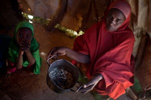 Una madre sostiene una olla vacía dentro de su casa improvisada en un asentamiento cerca de la ciudad de Ainabo, Somalia, en marzo de 2017. Foto: Kate Holt / Unicef