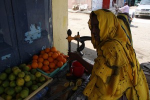 Una mujer vende jugo fresco en la calle para saciar la sed de los transeúntes bajo el sol abrasador de Yibuti. Crédito: James Jeffrey/IPS.