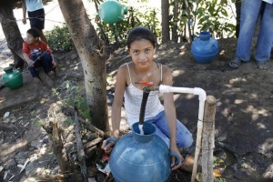 Una niña llena su cántaro de agua de la toma colectiva en la comunidad de Los Pinos, en el occidente de El Salvador. Conexiones públicas y gratuitas como estas palían los problemas de acceso al agua en los hogares rurales que carecen de conexión por tuberías. Crédito: Edgardo Ayala/IPS