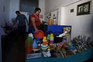 Dos comerciantes por cuenta propia colocan en una mesa productos para la venta en el interior de una vivienda privada, en el centro histórico de Villa de Remedios, en la central provincia de Villa Clara, en Cuba. Este tipo de negocios informales prospera en Cuba. Crédito: Jorge Luis Baños/IPS