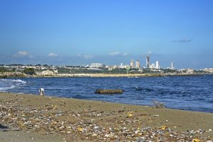 Un hombre busca objetos entre los desechos esparcidos en las contaminadas arenas de la playa El Gringo, en el municipio de Bajos de Haina, el principal centro industrial y portuario de República Dominicana. Crédito: Dionny Matos/IPS