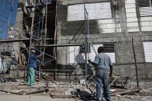 Dos trabajadores laboran en la reconstrucción de un edificio que resultó dañado por el paso del huracán Sandy en 2012 por la ciudad de Santiago de Cuba, en el oriente de la isla caribeña. Crédito: Jorge Luis Baños/IPS