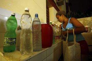 Una residente en uno de los municipios de La Habana organiza en su hogar los envases con agua potable que acaba de acarrear desde la calle, tras días sin suministro del recurso en su vivienda en la capital de Cuba. Crédito: Jorge Luis Baños/IPS