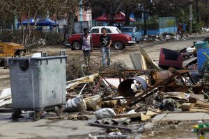 Dos personas caminan el miércoles 13 de septiembre en medio de los escombros y objetos esparcidos por una calle del barrio del Vedado tras el paso del huracán Irma por la capital de Cuba. Crédito: Jorge Luis Baños/IPS