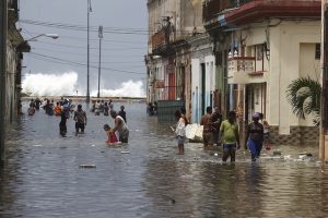 Residentes de La Habana transitan por una calle vecina al malecón de la capital de Cuba, inundada por la embestida del mar tras el paso del huracán Irma. Crédito: Jorge Luis Baños/IPS