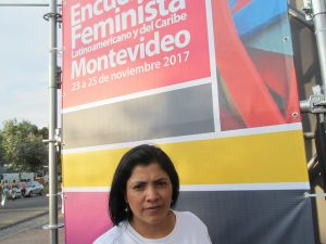 Yanet Caruajulca, activista peruana por el derecho al agua y a un ambiente sano, ante un cartel del 14 Encuentro Feminista Latinoamericano y del Caribe en la capital de Montevideo, donde uno de los ejes fue el análisis de los ataques con sesgo de género de los que son víctimas las defensoras de derechos en la región. Crédito: Mariela Jara/IPS