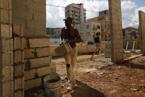 Un trabajador coloca bloques de construcción elaborados artesanalmente en la construcción de parte de una vivienda vecina a una zona afectada por los efectos del huracán Irma, en el barrio del Vedado, en la capital de Cuba. Crédito: Jorge Luis Baños/IPS