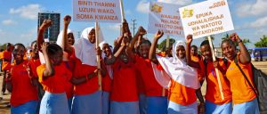 Niñas vestidas con el color naranja de la campaña del activismo para erradicar la violencia hacia las mujeres, se manifiestan en Dar es Salaam, en Tanzania. Un letrero dice: "Absténgase de usar lenguaje ofensivo para mujeres y niñas". Crédito: Deepika Nath/ONU Mujeres