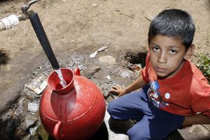 Un niño llena su cántaro de agua en una toma colectiva en Los Pinos, una comunidad del municipio de Tacuba, en el occidental departamento de Ahuachapán, en El Salvador. El acceso al agua potable en muchas comunidades rurales de América Central se mantiene como una carencia. Crédito: Edgardo Ayala/IPS