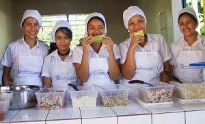 Alumnas del Centro Escolar Cantón Pepenance, en el municipio de Atiquizaya, en el occidente de El Salvador, frente a uno de los refrigerios diarios que se brindan a los estudiantes, altamente nutritivos y elaborados con productos de agricultores locales. Crédito: Edgardo Ayala/IPS