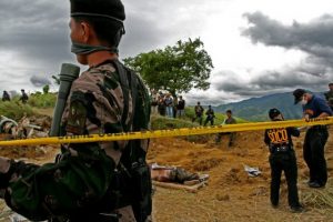 Un comando de la policía vigila mientras los investigadores desentierran a las víctimas de la masacre de Ampatuan. Crédito: InterAksyon