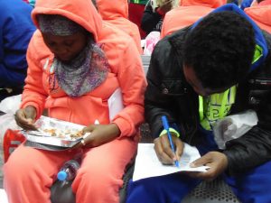 Emigrantes retornados comen algo mientras llenan papeles para la OIM en el aeropuerto de Nsimalen, en Yaundé, Camerún. Crédito: Mbom Sixtus/IPS.
