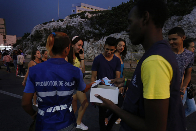 Una pareja de promotores de salud reparten preservativos a un grupo de adolescentes en la entrada de un concierto en el barrio del Vedado, en La Habana, la capital cubana. Crédito: Jorge Luis Baños/IPS