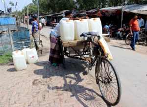 En la localidad costera de Satkhira, en el sudoeste de Bangladesh, donde las fuentes de agua dulce sufren la intrusión de agua salada, un vendedor de agua llena tanques de 20 litros en cañerías públicas para vender en islas donde las familias destinan unos 300 takas (3,59 dólares) al mes para comprar agua potable para beber y cocinar. Crédito: Manipadma Jena/IPS.