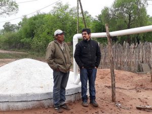 El wichí Mariano Barraza (I), junto a Enzo Romero, técnico de la organización Fundapaz, junto a la cisterna construida para almacenar agua de lluvia en la comunidad indígena de Lote 6, para enfrentar los seis meses de sequía que soporta cada año esta zona de la provincia de Salta, en el Chaco, en el norte de Argentina. Crédito: Daniel Gutman/IPS