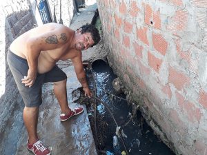 José Pablo Zubieta muestra una de las mangueras con las que las distintas viviendas de Villa La Cava realizan sus conexiones informales para abastecerse de agua. El servicio se suministra unas pocas horas al día y el agua llega contaminada a este asentamiento precario unos 10.000 habitantes al norte de la capital argentina. Crédito: Daniel Gutman/IPS