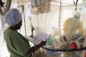 Trabajadores de salud hablan con un paciente de ébola que permanece aislado, en un Centro de Tratamiento de Ébola, en Beni, República Democrática del Congo. Se han encontrado dos medicamentos para tratar con éxito al letal virus, porque permite a las comunidades el tratamiento temprano de los enfermos. Crédito: OMS