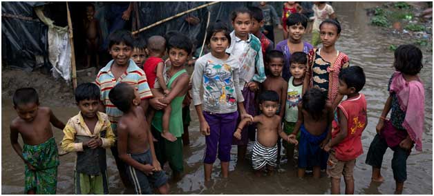Niños refugiados rohinyá en medio de las aguas que inundan su precario asentamiento en Bangladesh, tras el paso de una tormenta. Crédito: Unicef