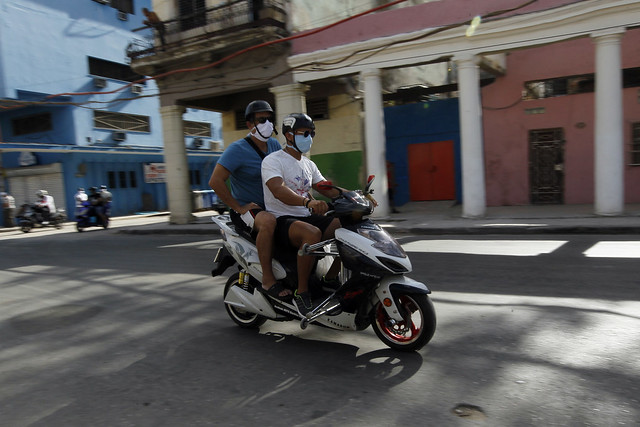 El líder del club cubano de Moto Eléctrica Osdany Fleites Nuñez traslada a su padre a una consulta médica, en el capitalino municipio de Centro Habana, en La Habana. Se calcula que actualmente unas 200 000 motocicletas eléctricas transitan por la capital cubana. Foto: Jorge Luis Baños/IPS