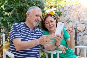 Una pareja de adultos mayores mira la pantalla de un móvil. Foto: Gulcin Ragiboglu/ Shutterstock