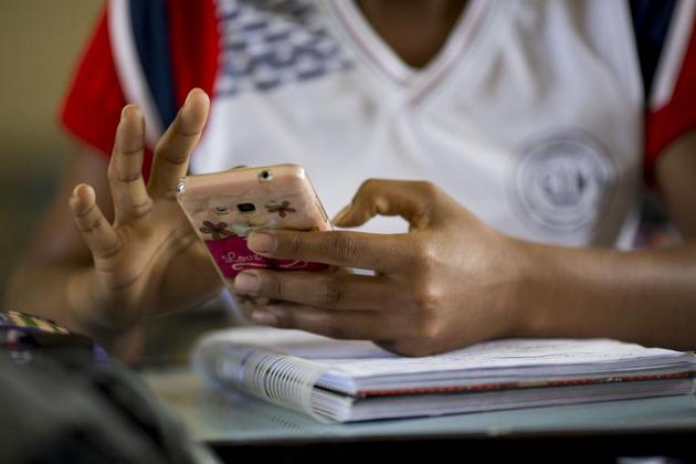 Una estudiante en Brasil emplea su teléfono móvil. Los recursos para proseguir la enseñanza a distancia, como consecuencia de la pandemia, elevan los costos de la educación y ahondan el déficit en su financiamiento. Foto: Unesco