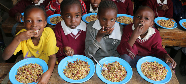 Niños en Kenia disfrutan un almuerzo con vegetales desestimados para la exportación por no tener la forma "estéticamente correcta". No desperdiciar alimentos y mejorar las dietas puede contribuir con el clima, según el Pnuma. Foto: Martin Karimi/PMA
