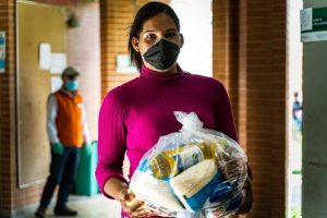 Dayana, una migrante de Venezuela, recibe ayuda con comestibles del Programa Mundial de Alimentos en Bogotá. Asistir a migrantes y desplazados en los países de acogida es un requisito para combatir el hambre en tiempos de pandemia. Foto: PMA