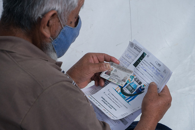 El señor Abel revisa que sus datos estén escritos de forma correcta en la hoja de registro mientras espera su turno para recibir la vacuna. Foto: Isabel Briseño/Pie de Página